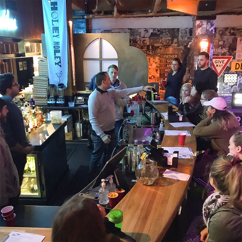 Man standing in a bar talking to a crowd of people