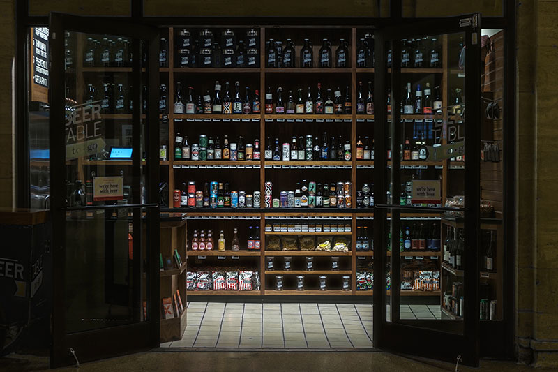 Rows of alcohols on a shelves in a room with an open door