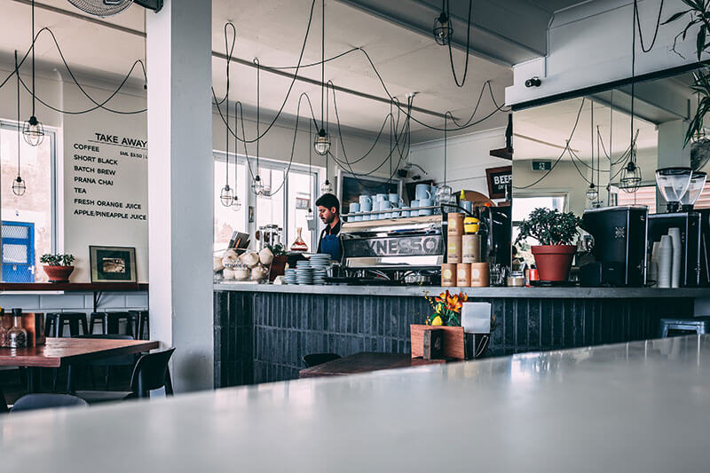 Long shot of an empty cafe with the barista in the distance behind the bar