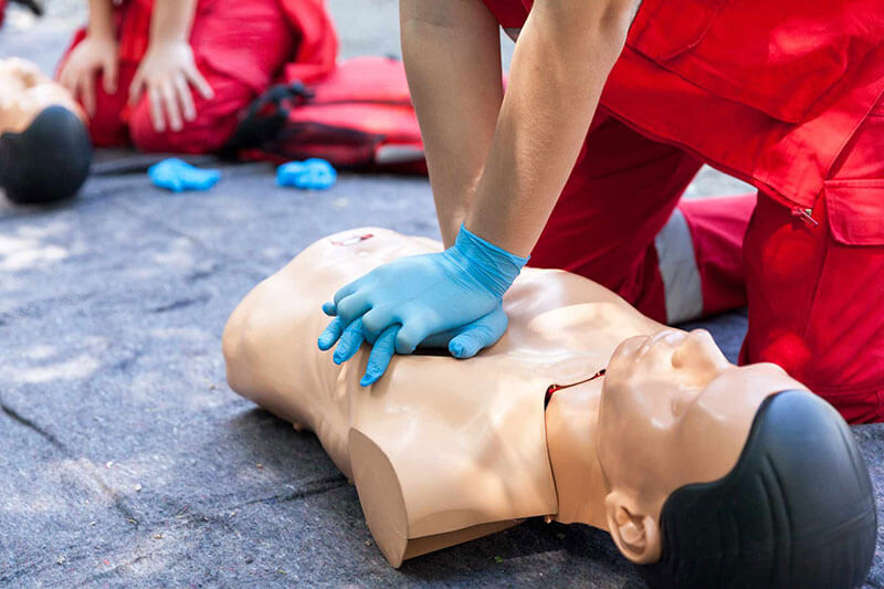 Ambulance worker in training gives CPR to dummy