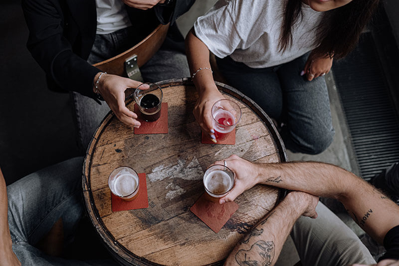 Top view of wooden table with people holding drinks around it